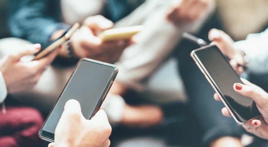 Auf dem Bild ist ein Kreis von mehreren Leuten zu sehen, die ihr Smartphone in der Hand halten.