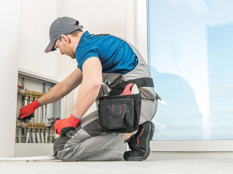 Ein Handwerker entlüftet eine Fußbodenheizung.