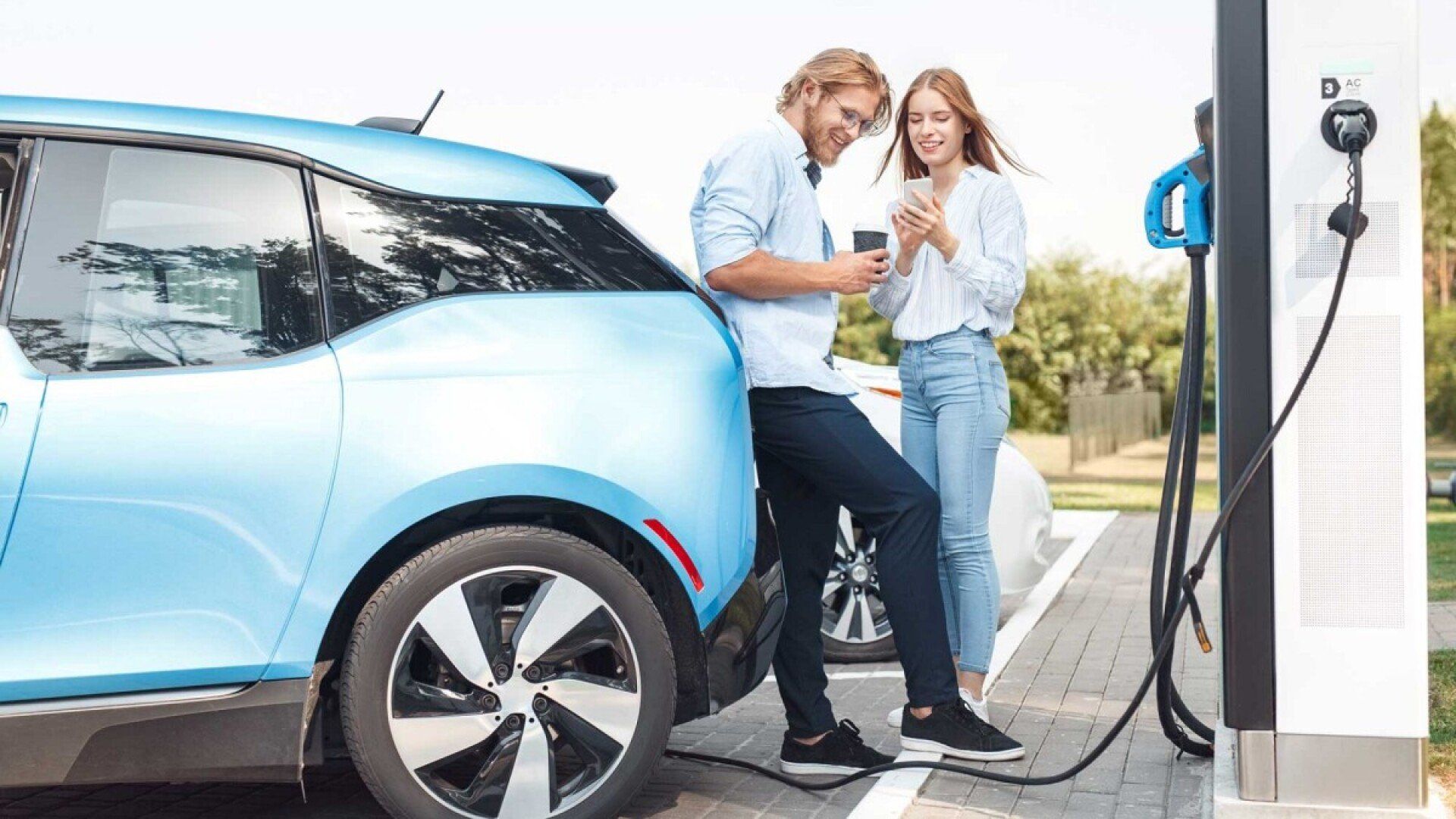 Ein junges Paar hat mit einer E-Auto App eine Ladesäule gefunden.