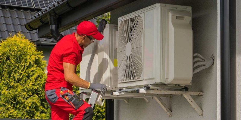 Ein Wartungsarbeiter überprüft die Luft-Luft-Wärmepumpe.