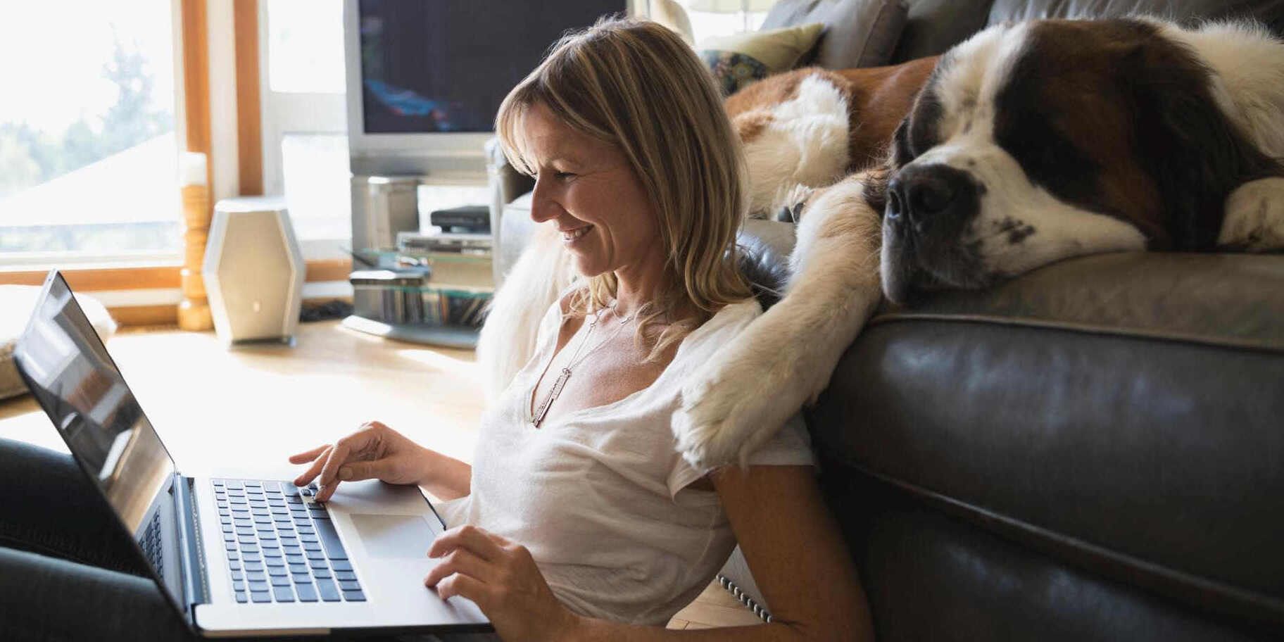Frau mit Hund schaut in Laptop