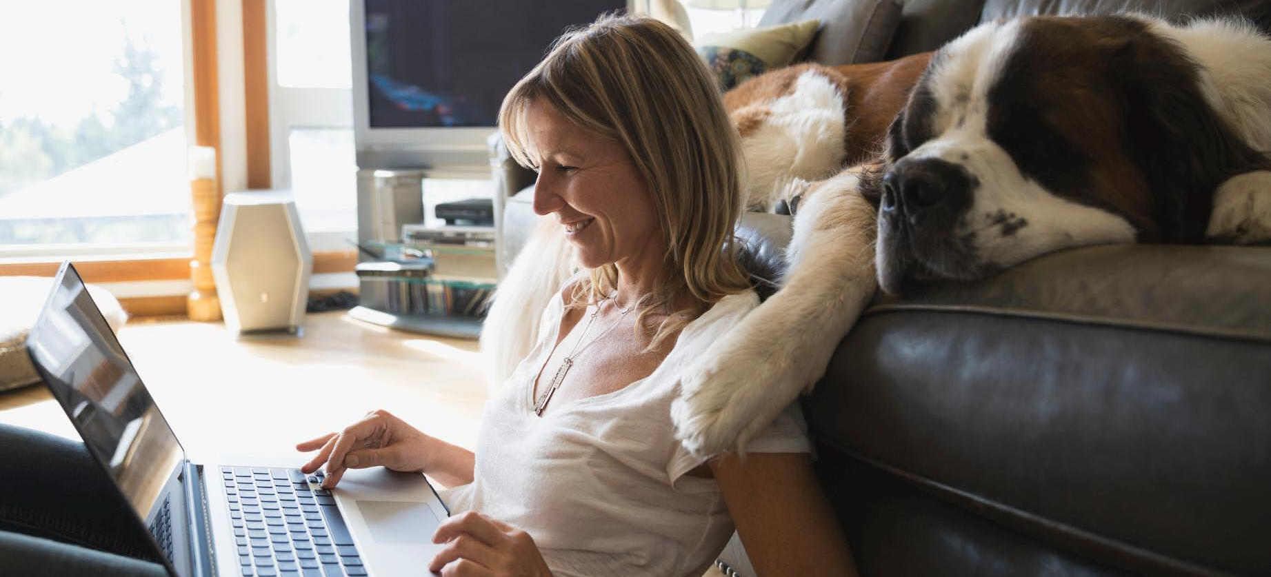 Frau mit Hund schaut in Laptop