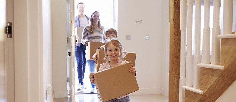 Familie geht mit Umzugskisten durchs Haus
