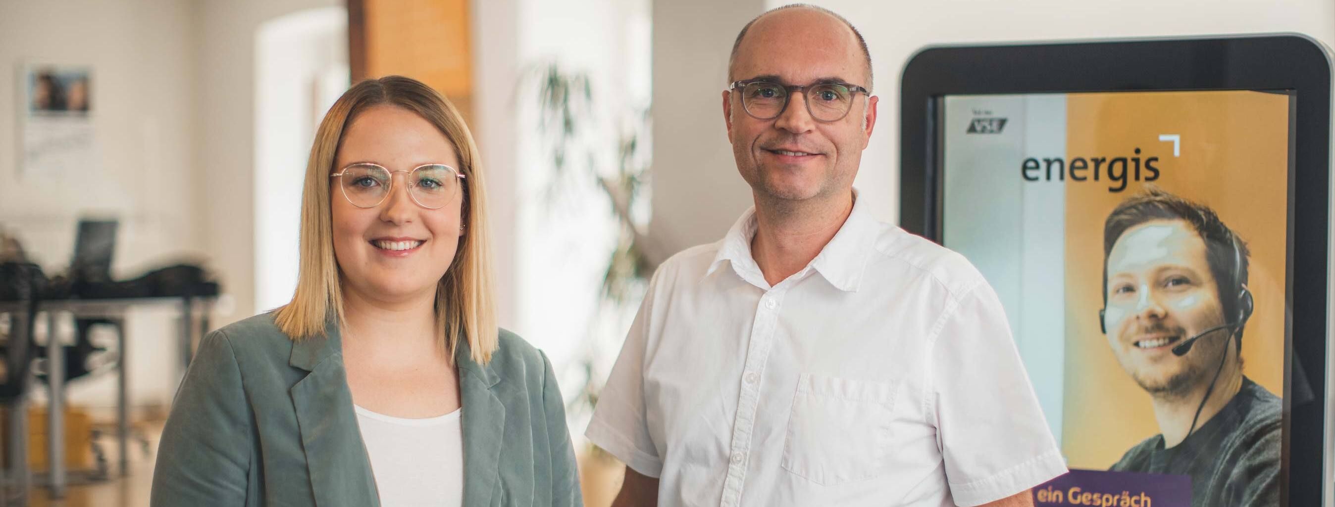 energis Kundenberater im Kundencenter vor Infostele