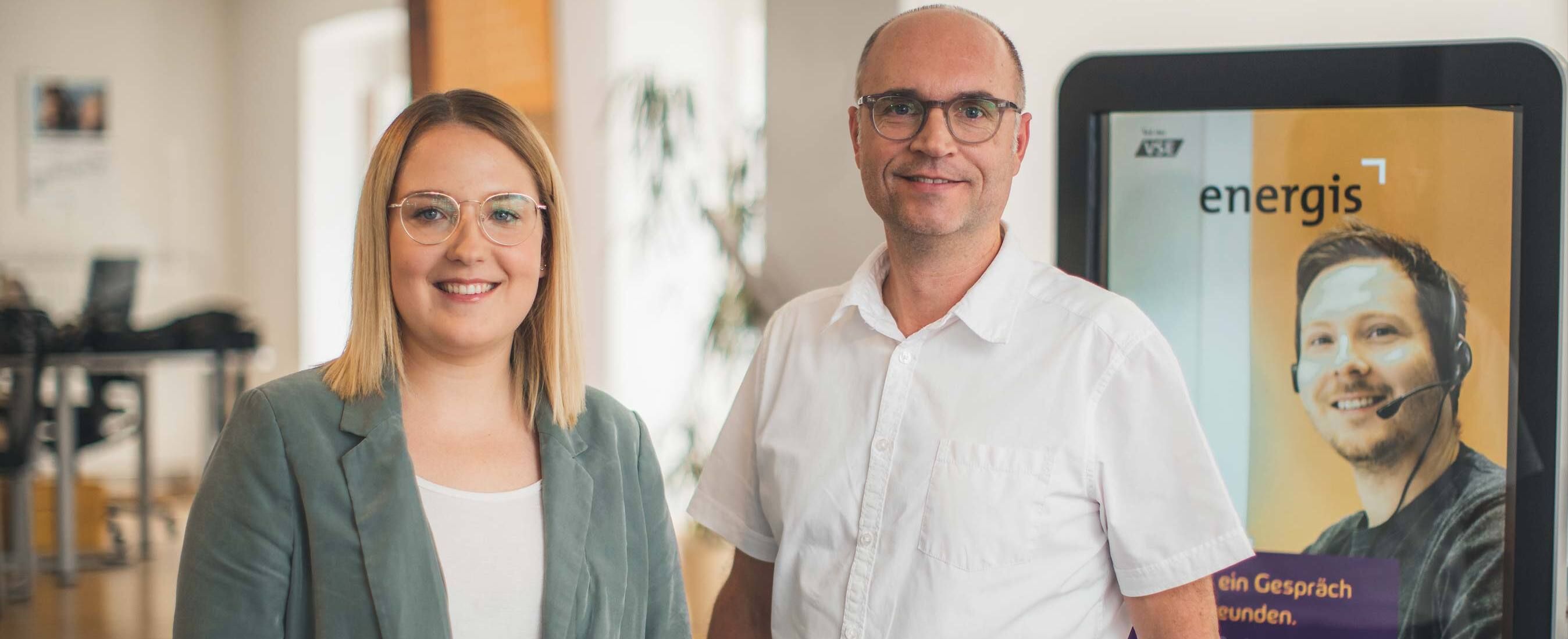 energis Kundenberater im Kundencenter vor Infostele