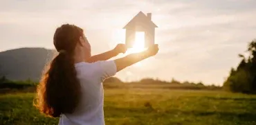 Kind mit Papphaus auf Feld im Sonnenuntergang